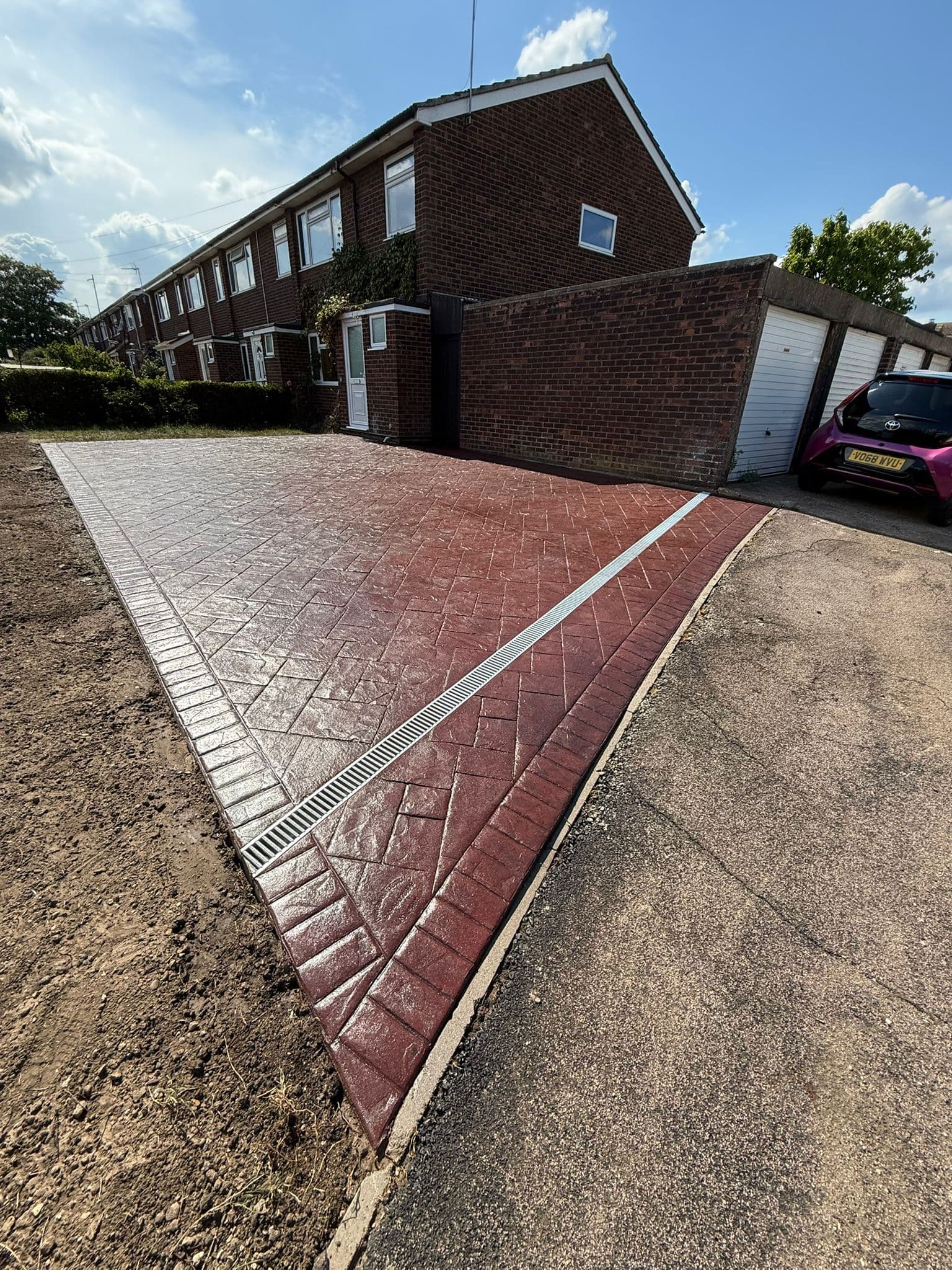 Terracotta red imprinted concrete driveway stamped in a herringbone brick pattern